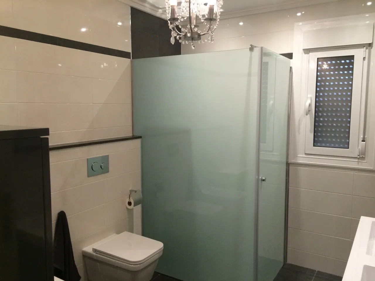Bathroom renovated by URPE Spain with glass shower screen and two-tone tiling