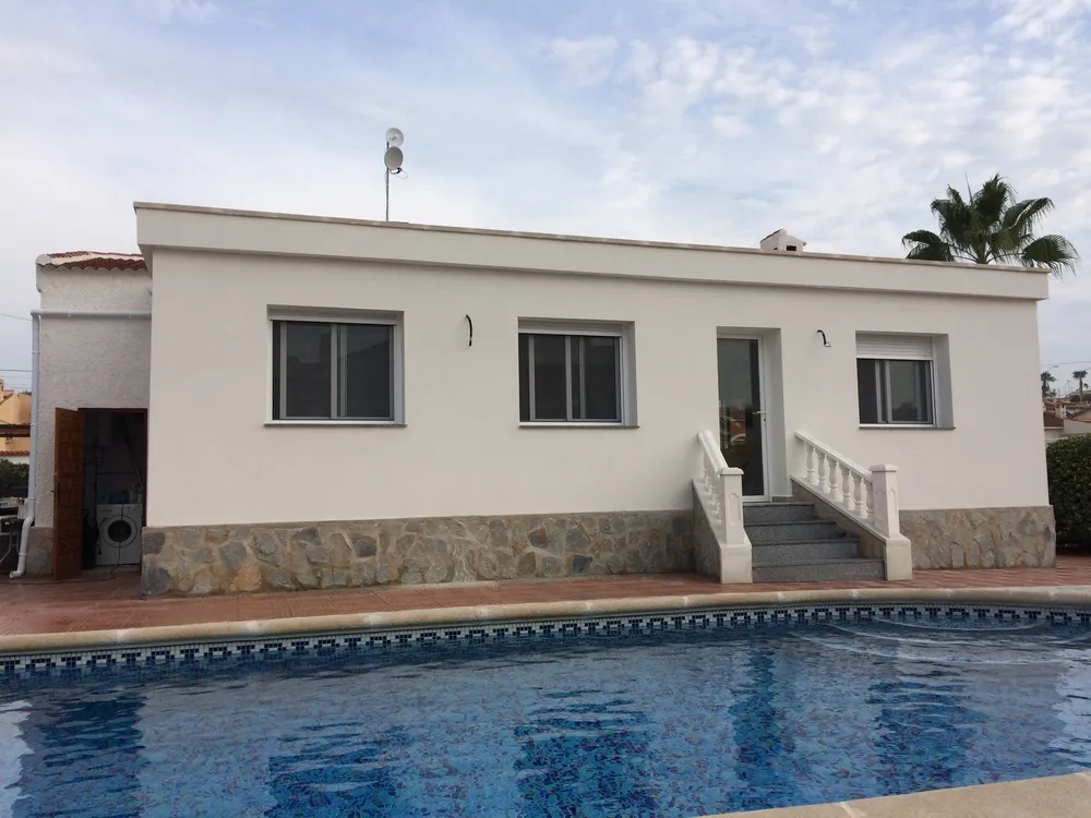 Vivienda reformada con piscina y zócalo de piedra